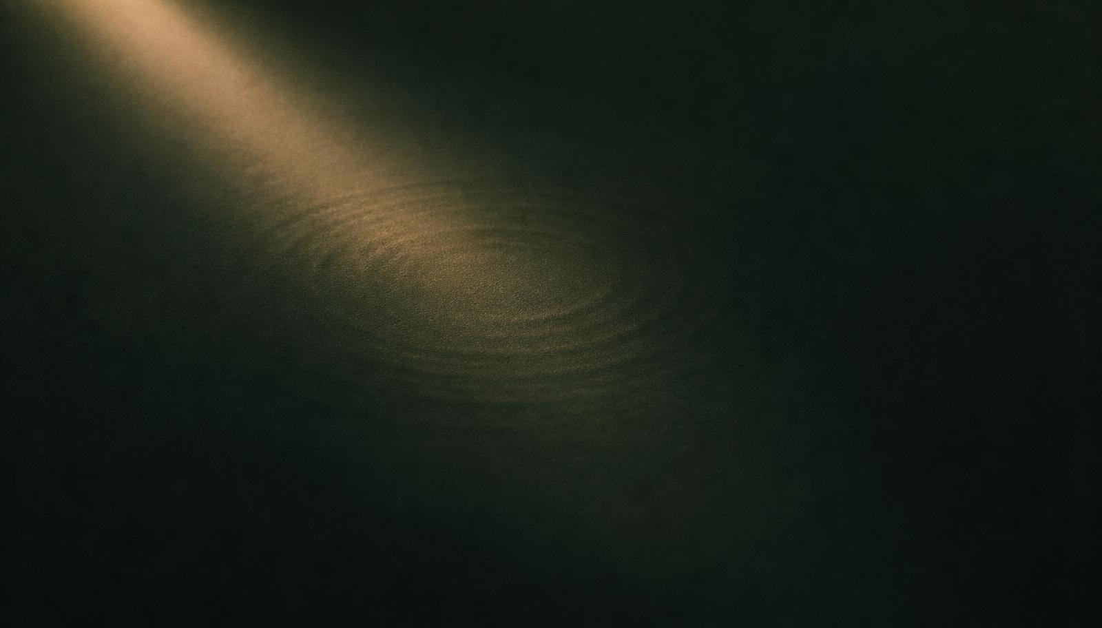A single shaft of light falling across a dark surface